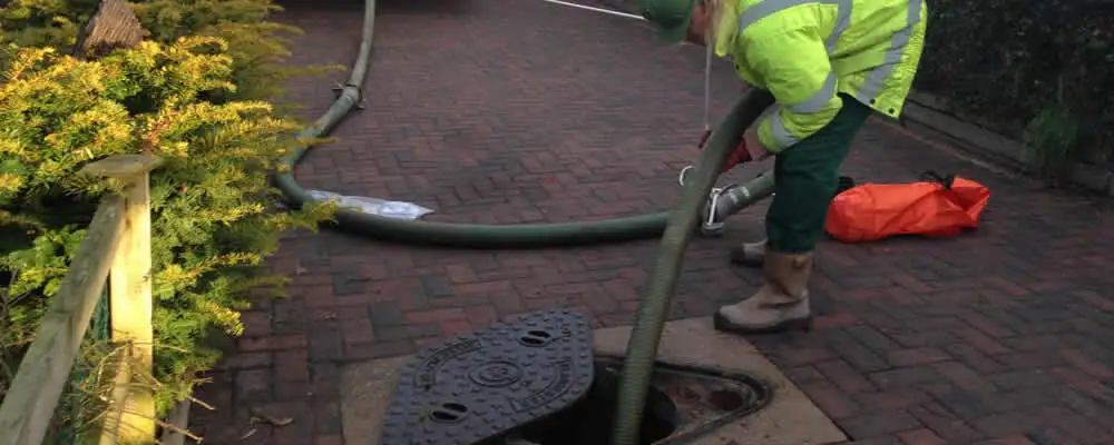 Septic tank cleaning technician servicing a septic tank with a vacuum hose in Santa Rosa, CA