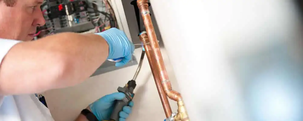 Water heater repair technician testing copper pipe connections and controls in Santa Rosa, CA